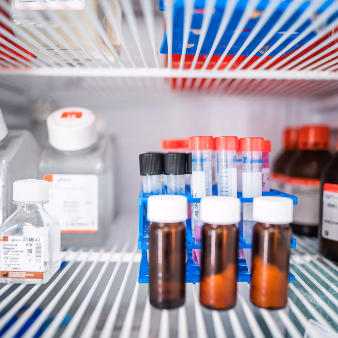Monsterflesjes en laboratoriumreagentia opgeslagen in een gekoelde laboratoriumkast voor analyse en kwaliteitscontrole.