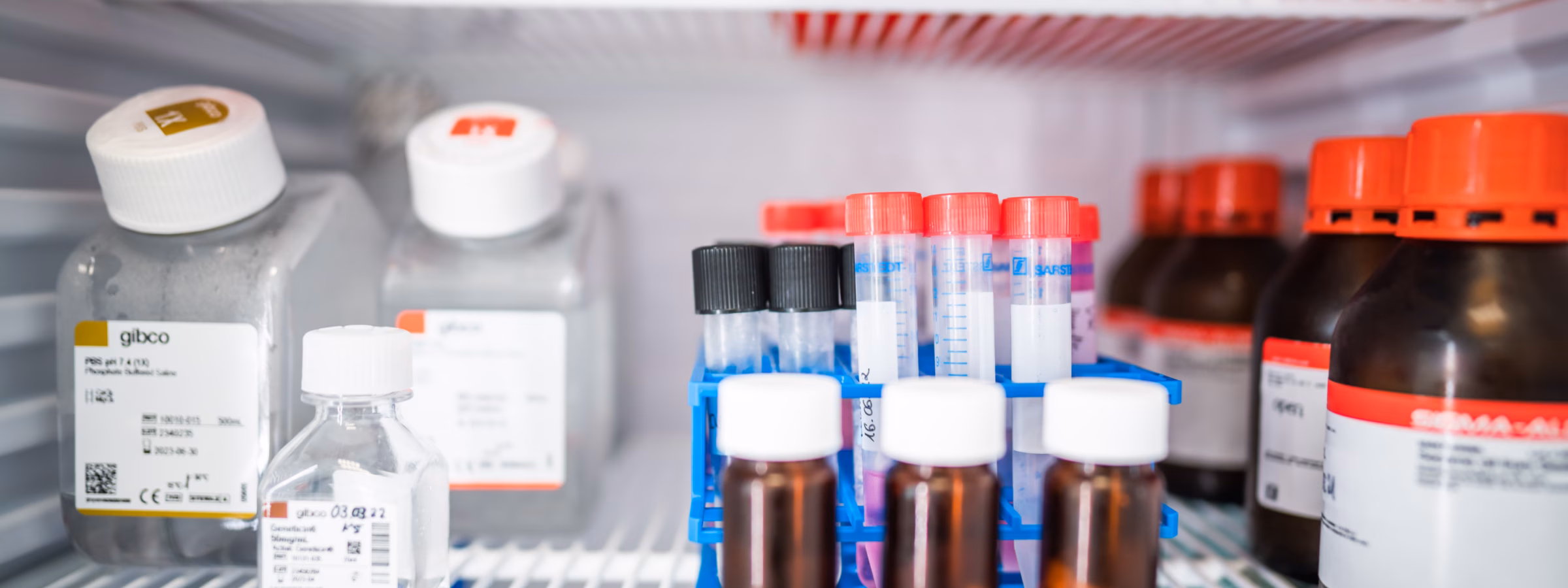 Monsterflesjes en laboratoriumreagentia opgeslagen in een gekoelde laboratoriumkast voor analyse en kwaliteitscontrole.