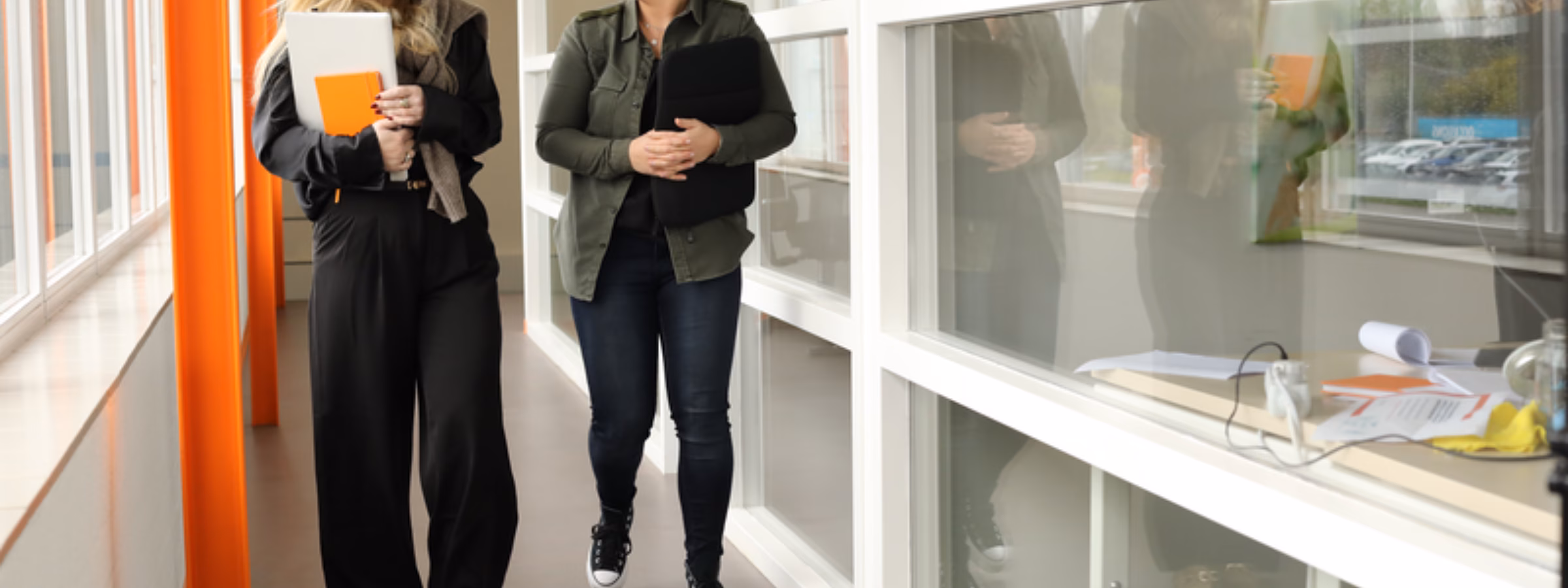 Twee medewerkers lopen door een kantooromgeving en bespreken werkzaamheden.