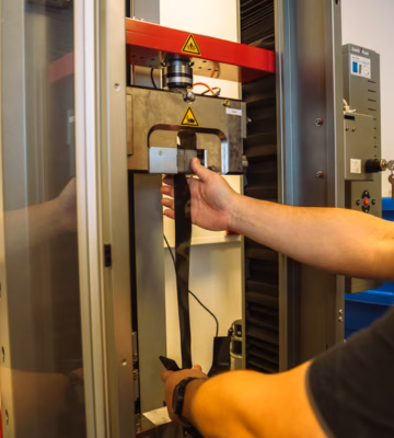 Medewerker bedient een industriële testmachine voor het uitvoeren van mechanische materiaalproeven.