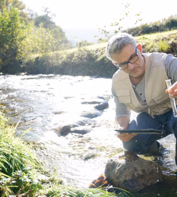 Un échantillon d'eau est prélevé dans un ruisseau à des fins d'analyse de la qualité de l'eau et de surveillance environnementale.