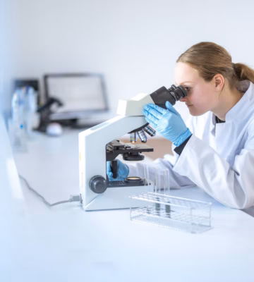 Un technicien de laboratoire analyse un échantillon à l'aide d'un microscope dans un environnement de laboratoire.