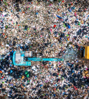 Photo aérienne d'un site de traitement des déchets avec des véhicules et de grandes quantités de déchets mixtes.