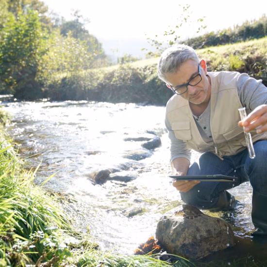 Een watermonster wordt genomen in een beek voor onderzoek naar waterkwaliteit en milieumonitoring.