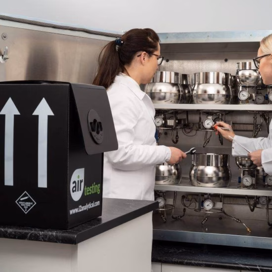 Twee medewerkers controleren meetapparatuur voor lucht- en gasanalyses in een laboratoriumomgeving.