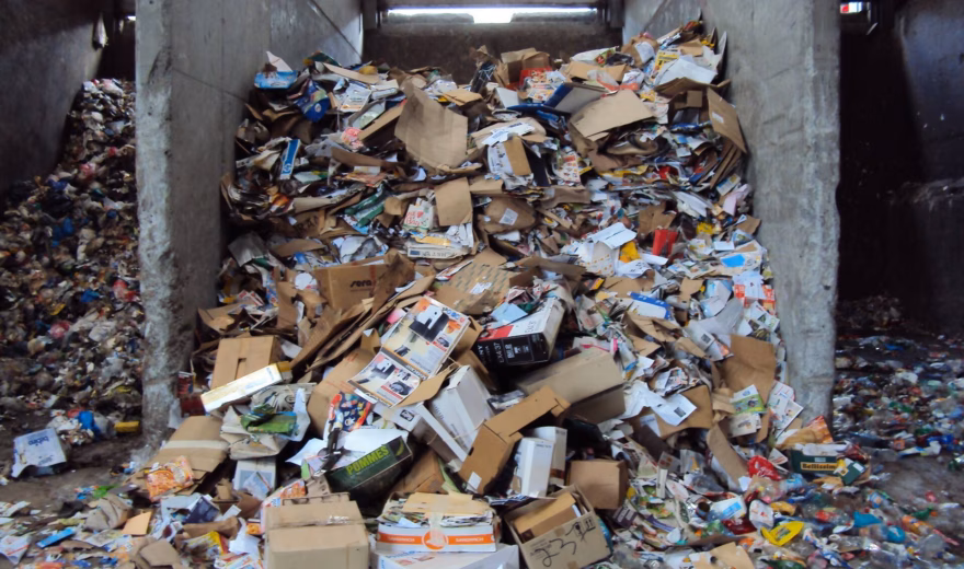 Gemengd afval en karton op een sorteer- of overslaglocatie voor afvalverwerking.