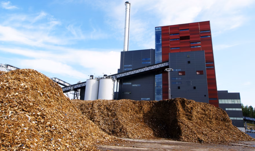 Biomassacentrale met grote hopen houtsnippers op een industrieterrein voor duurzame energieopwekking.