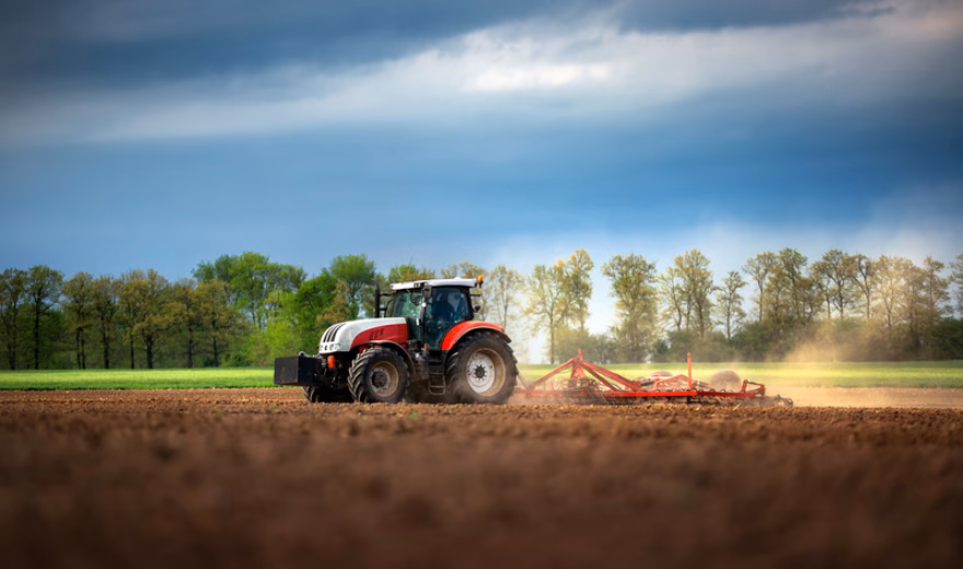 A tractor is tilling farmland in a field during outdoor fieldwork.