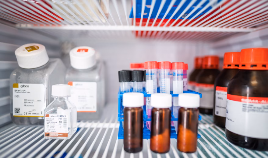 Monsterflesjes en laboratoriumreagentia opgeslagen in een gekoelde laboratoriumkast voor analyse en kwaliteitscontrole.