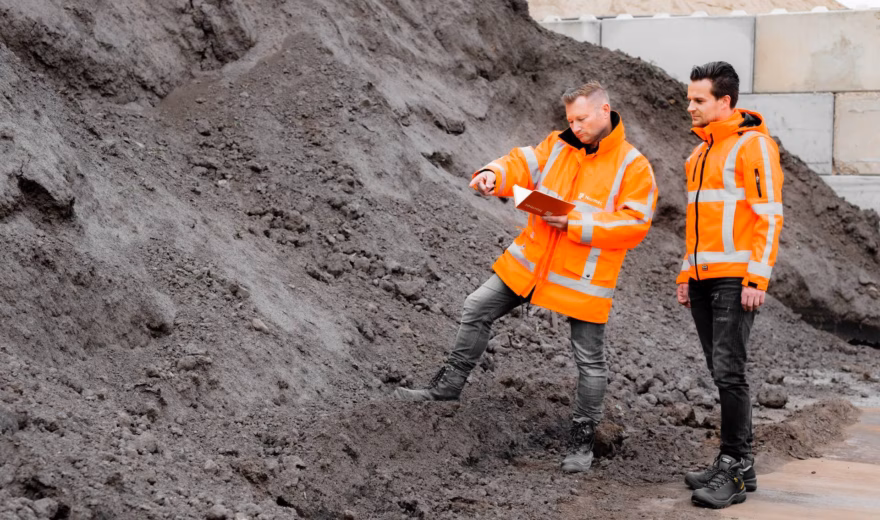 Medewerkers beoordelen opgeslagen grond en registreren bevindingen voor bodemonderzoek.