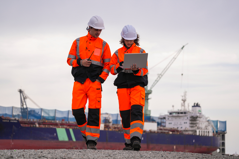 Two inspectors are checking and recording data at an industrial site in a port area.
