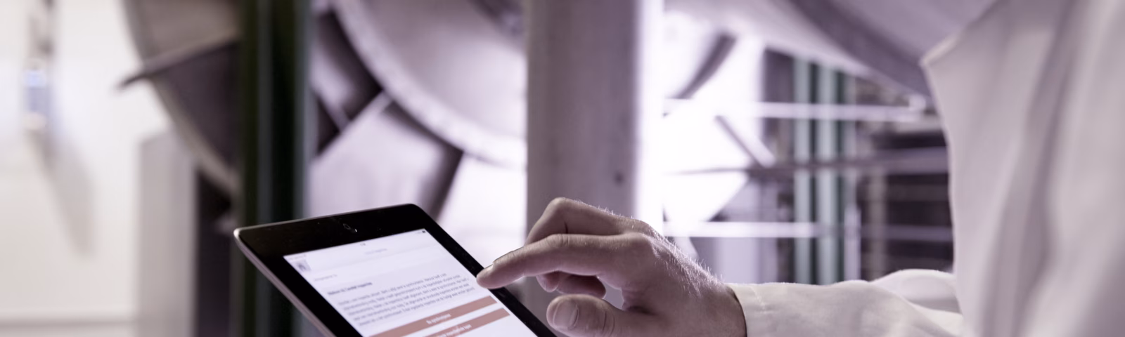 An employee checks digital data on a tablet in a production environment.