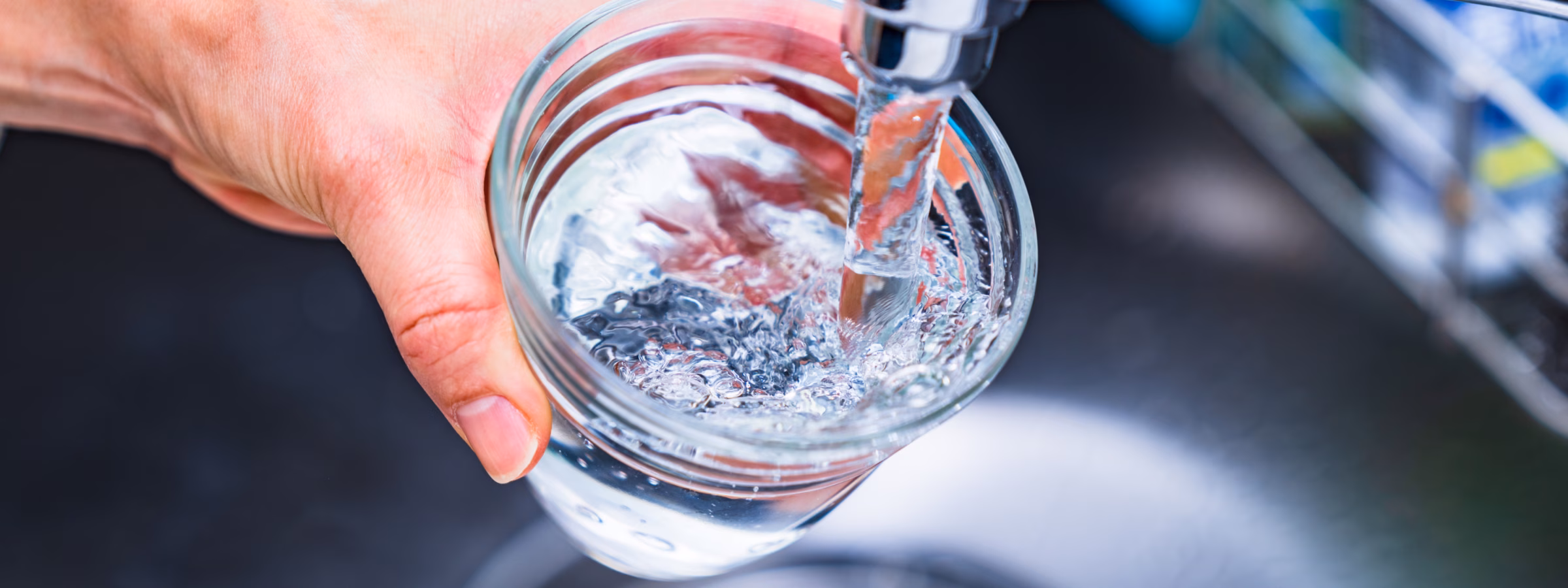 Watermonster wordt afgenomen uit een kraan in een glazen pot voor wateronderzoek.