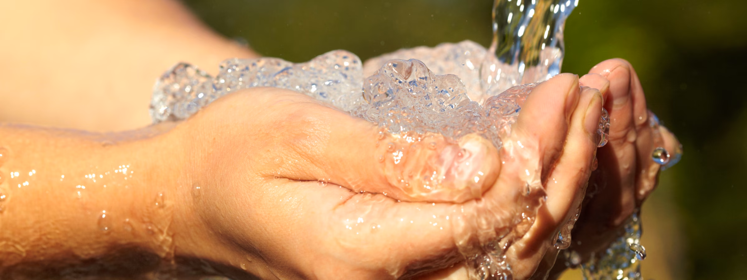 Handen opgevangen onder stromend water uit een natuurlijke waterbron.