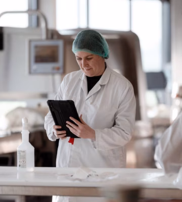 Medewerker in een productieomgeving controleert gegevens op een tablet tijdens een kwaliteits- of procescontrole.