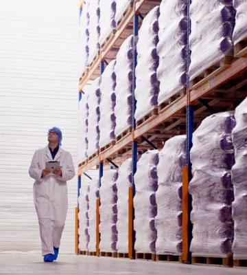 Medewerker controleert opgeslagen producten in een magazijnomgeving voor kwaliteits- en voorraadbeheer.