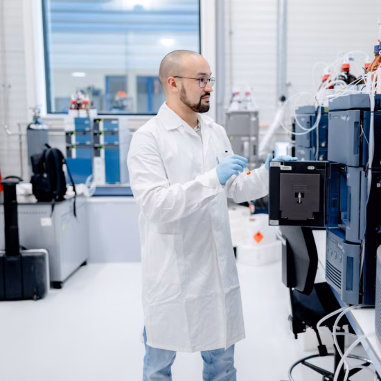 Laboratoriummedewerker bedient geavanceerde analyseapparatuur in een modern laboratorium.