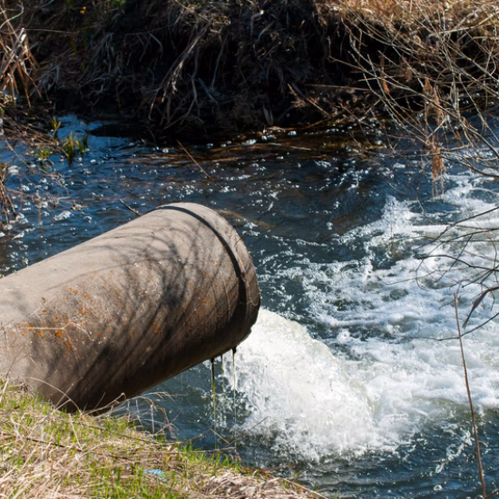 Water flows through a discharge pipe into a watercourse as part of water management and environmental monitoring.