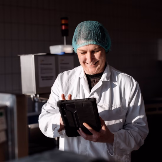 An employee uses a tablet for inspections, quality recording, and process monitoring in a production environment.