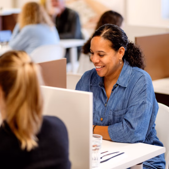 Medewerkers voeren een gesprek aan een werkplek in een professionele kantooromgeving.