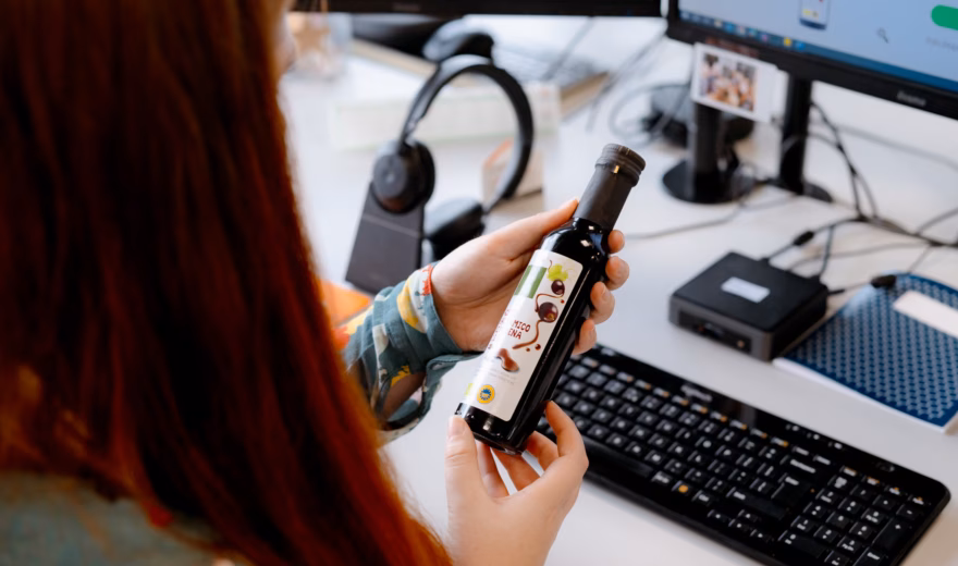Medewerker beoordeelt een voedingsproduct aan de hand van productinformatie op een computerscherm.