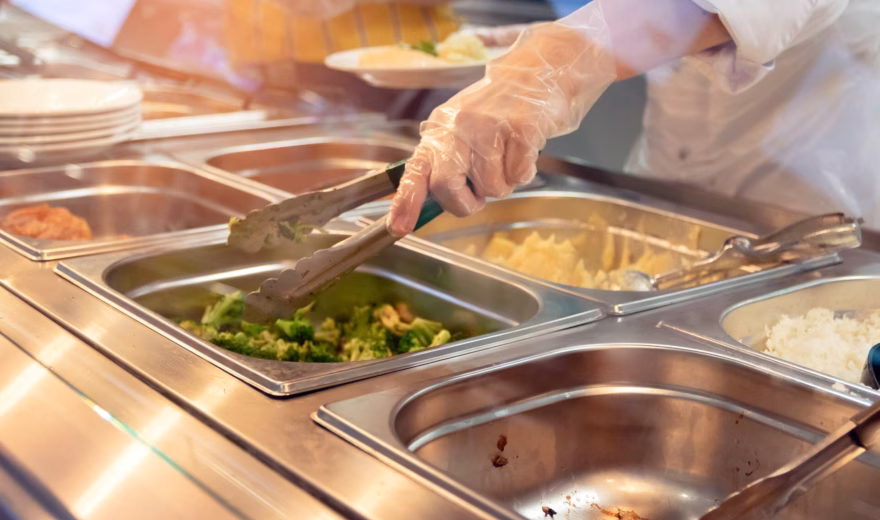 Buffet setup with warming trays and serving tongs during meal service