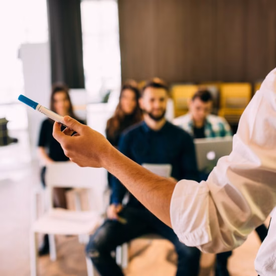 A presenter is conducting a training session for a group of participants in a classroom or training room.