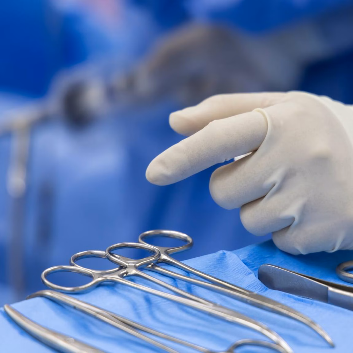 Steriele chirurgische instrumenten en handschoenen op een operatietafel tijdens een medische ingreep.