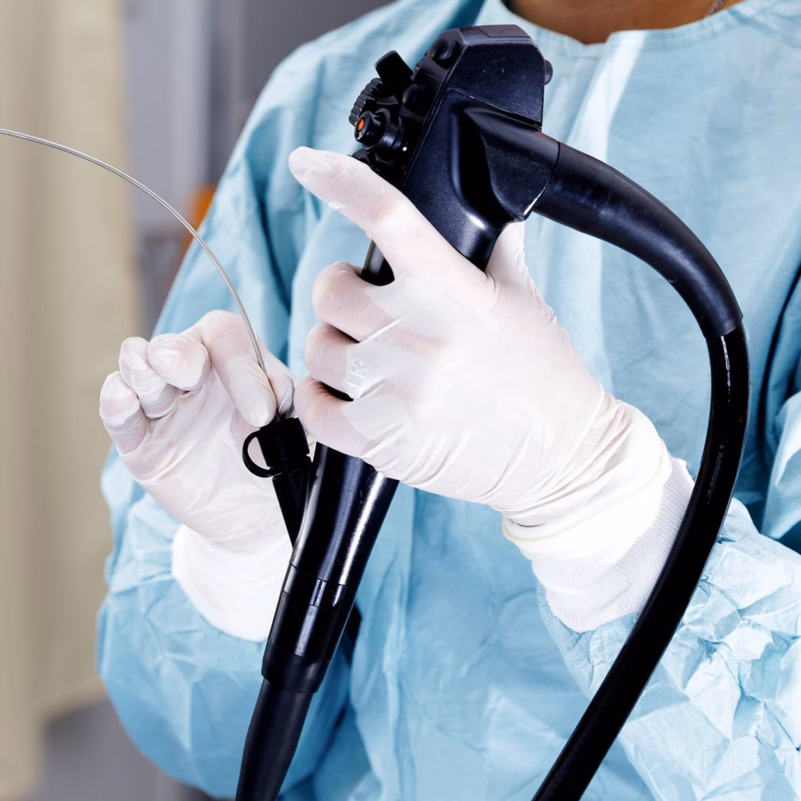 A medical specialist prepares an endoscope for examination or treatment in a clinical setting.