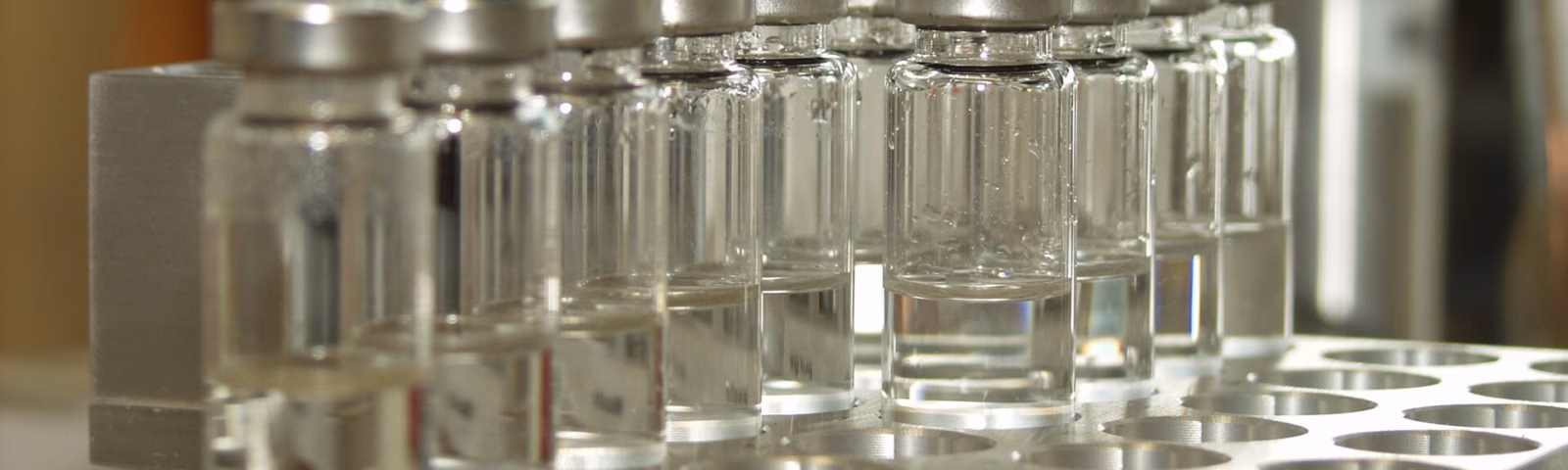 Row of glass sample vials in a holder for automated laboratory analysis.