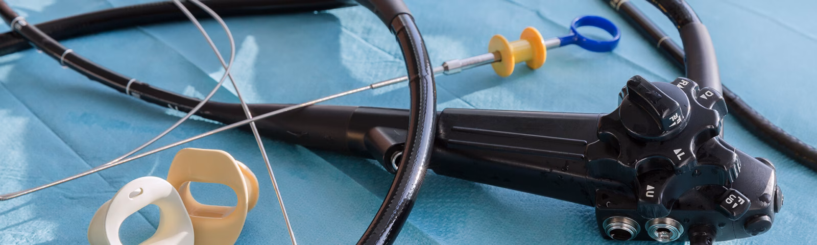 Endoscope with a flexible tube and medical instruments on a sterile surface.