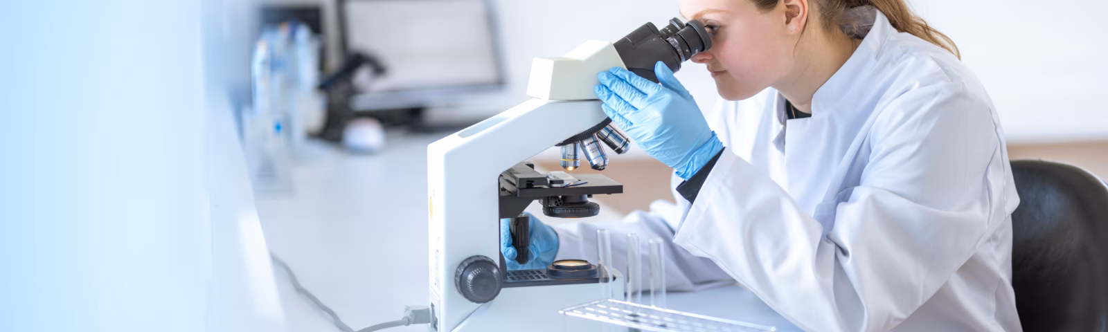 Een laboratoriummedewerker analyseert een monster met een microscoop in een laboratoriumomgeving.