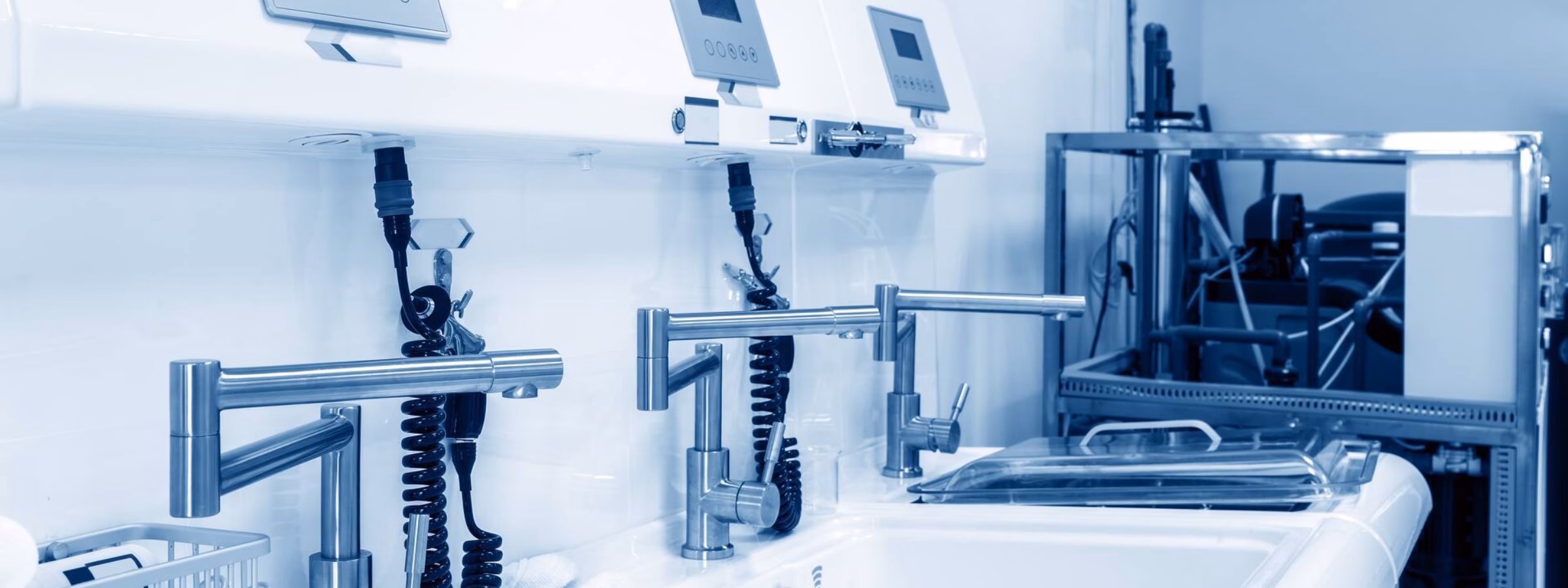 Steriele wasruimte met medische wastafels, dispensers en monitoringapparatuur voor hygiëne in een zorgomgeving.