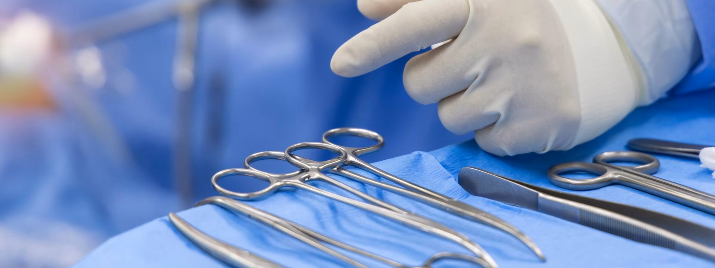 Steriele chirurgische instrumenten en handschoenen op een operatietafel tijdens een medische ingreep.