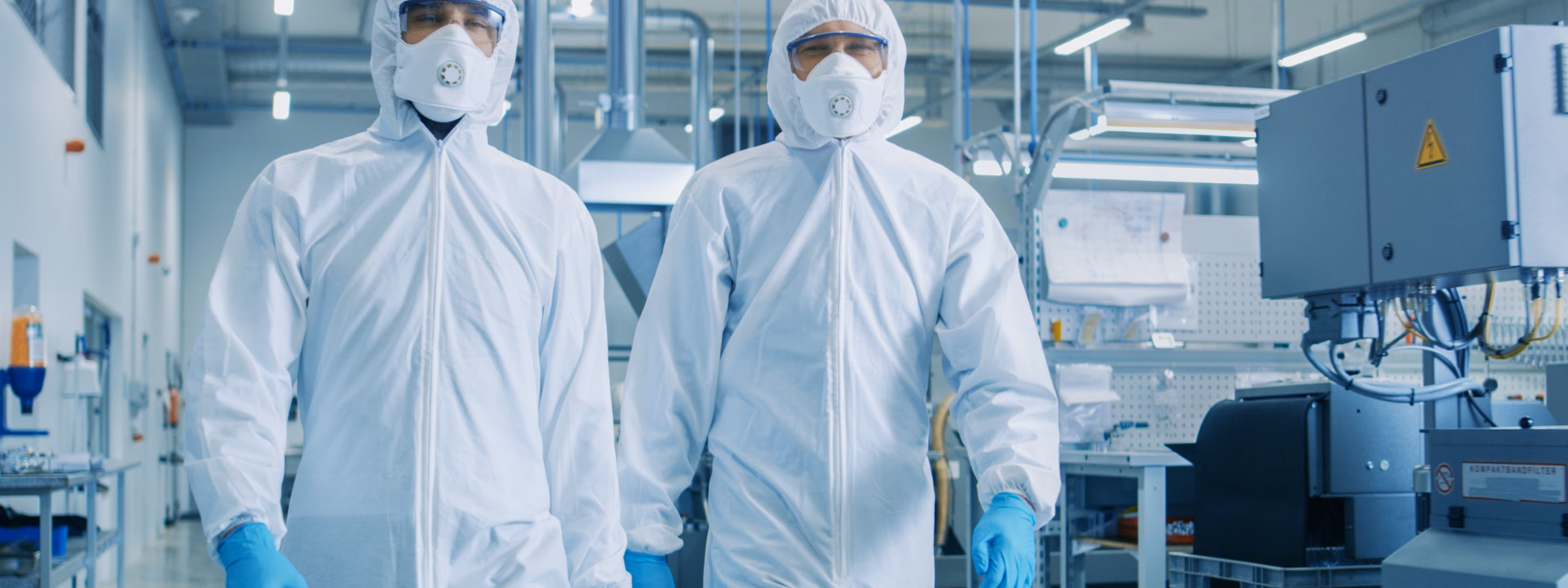 Two Engineers/ Scientists in Hazmat Sterile Suits Walking Through Technologically Advanced Factory/ Laboratory. Clean High-Tech Environment with CNC Machinery.