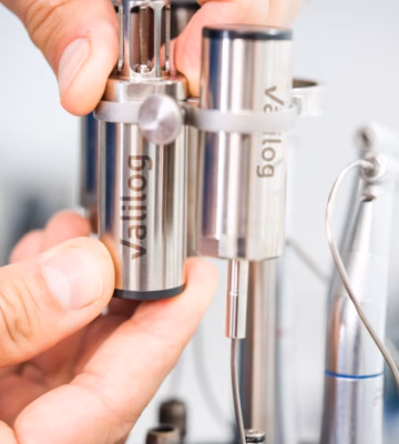 Eine Hand positioniert einen Metallsensor oder eine Messkomponente in einem Laborgerät zur Analyse und Kalibrierung