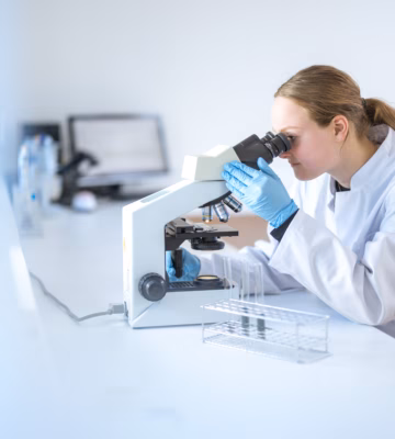 Een laboratoriummedewerker analyseert een monster met een microscoop in een laboratoriumomgeving.