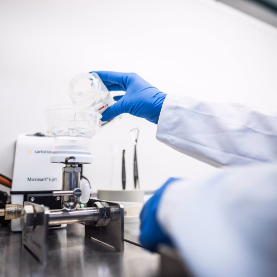 A laboratory technician holds a sample during analysis using laboratory equipment