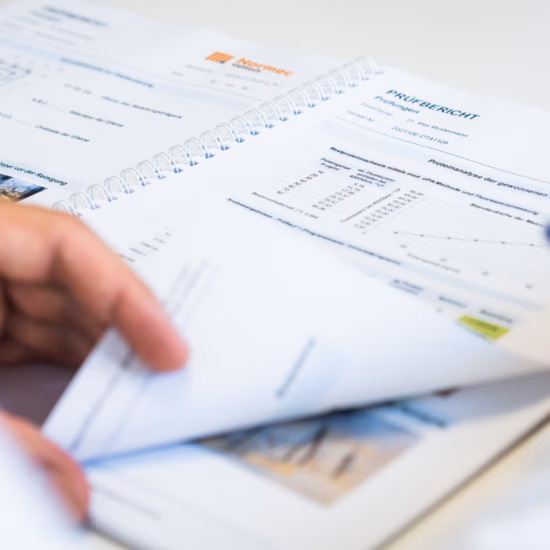 A person reviews and organizes report documents containing test results and analyses at a desk