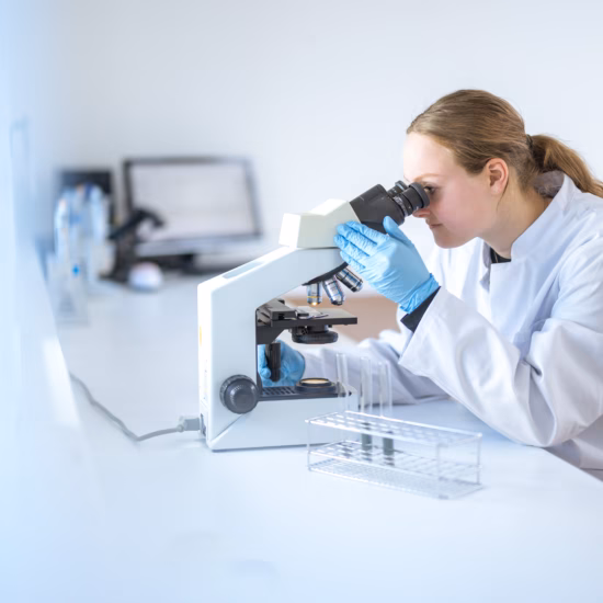 Een laboratoriummedewerker analyseert een monster met een microscoop in een laboratoriumomgeving.