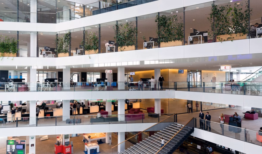 Modern kantoorgebouw met open atrium, meerdere verdiepingen en flexibele werkplekken.