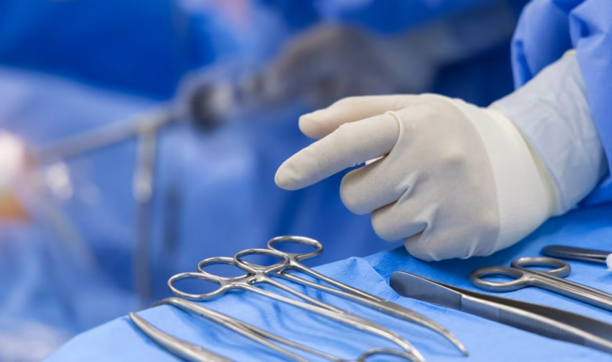 Steriele chirurgische instrumenten en handschoenen op een operatietafel tijdens een medische ingreep.