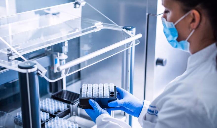 Laboratoriummedewerker plaatst of controleert monsters in een geautomatiseerd analysesysteem in een laboratorium