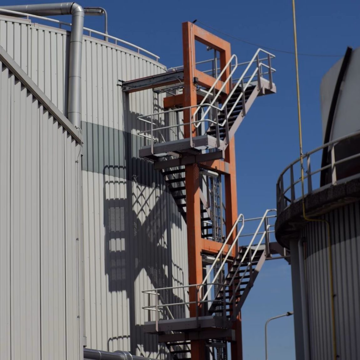 Échelle industrielle fixe et structure de plate-forme sur un site industriel, permettant l'accès aux installations en hauteur.