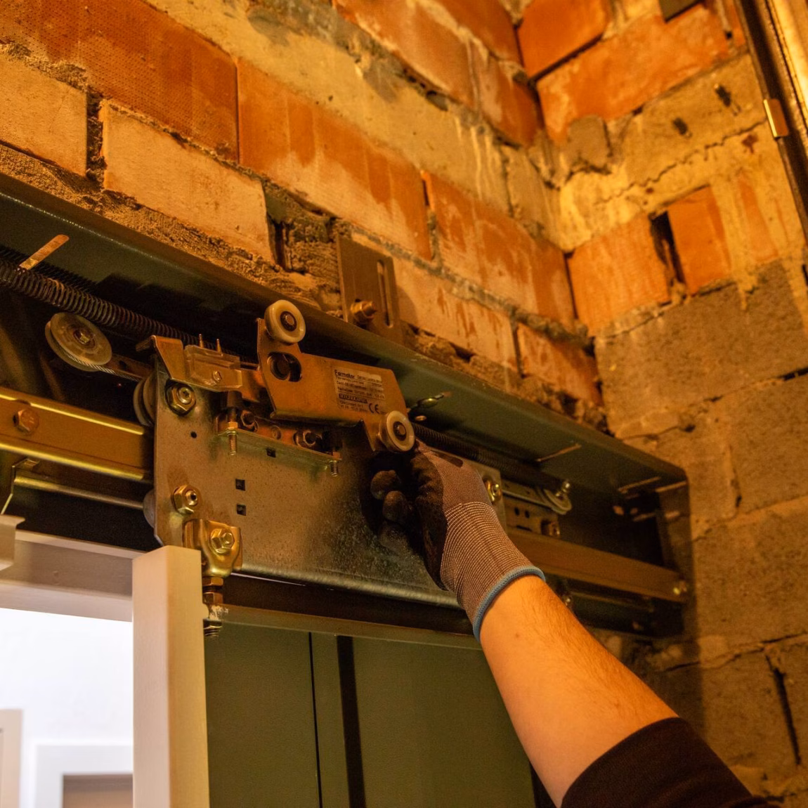 Ein Techniker führt eine Inspektion oder Einstellung eines Türmechanismus in einer bestehenden gemauerten Konstruktion durch.