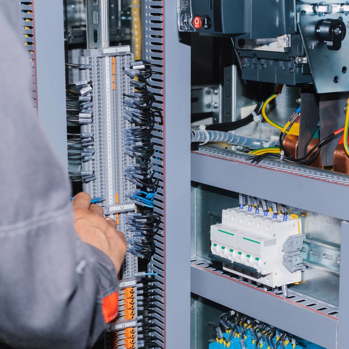 Technicus voert inspectie- of onderhoudswerkzaamheden uit aan een geopende elektrische schakelkast.