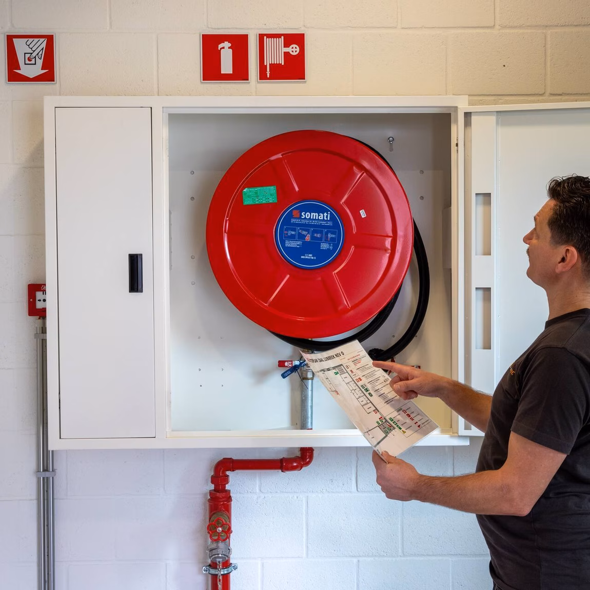 Inspection of a fire hose reel during a fire safety inspection in a building.