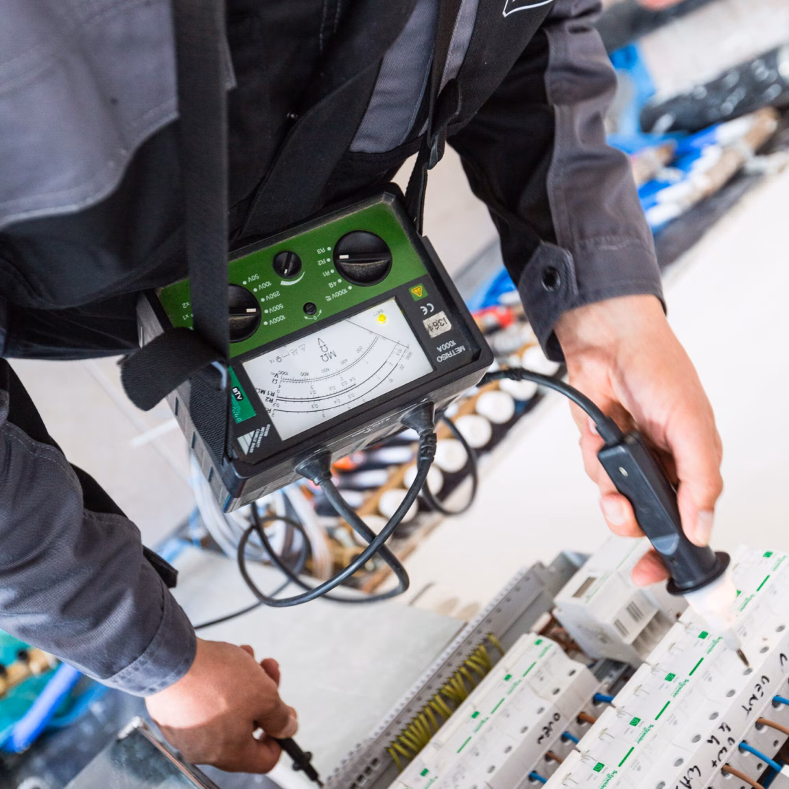 A technician is taking measurements on an electrical system for inspection and testing.
