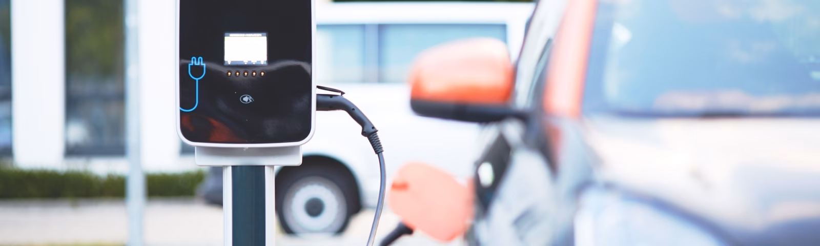 An electric car is charging at a charging station at a modern charging station for sustainable transportation.
