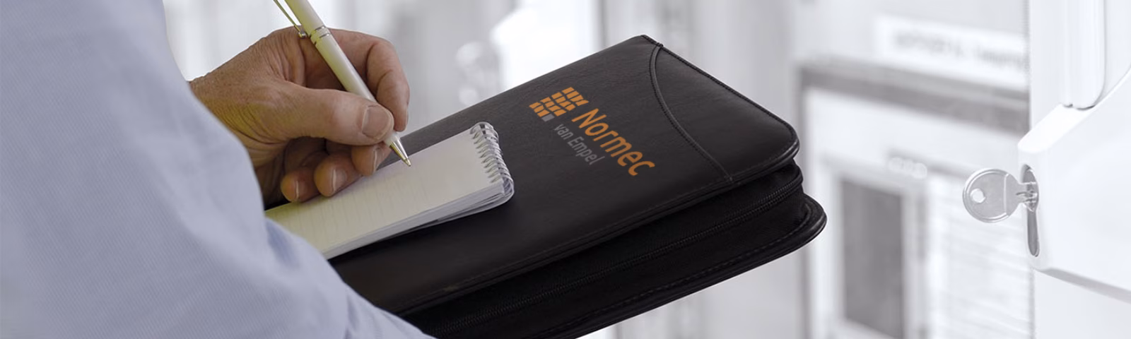 An employee records inspection findings for a technical installation using a documentation folder and a notepad.